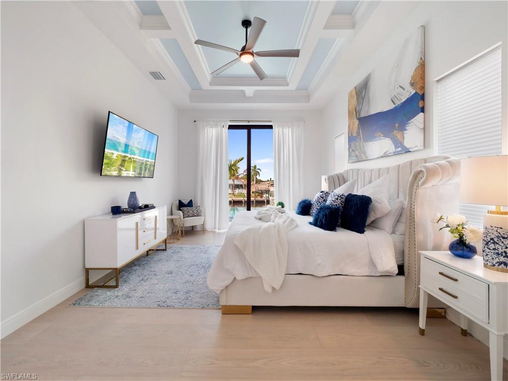 Bedroom with access to outside, ceiling fan, light wood-style floors, and coffered ceiling