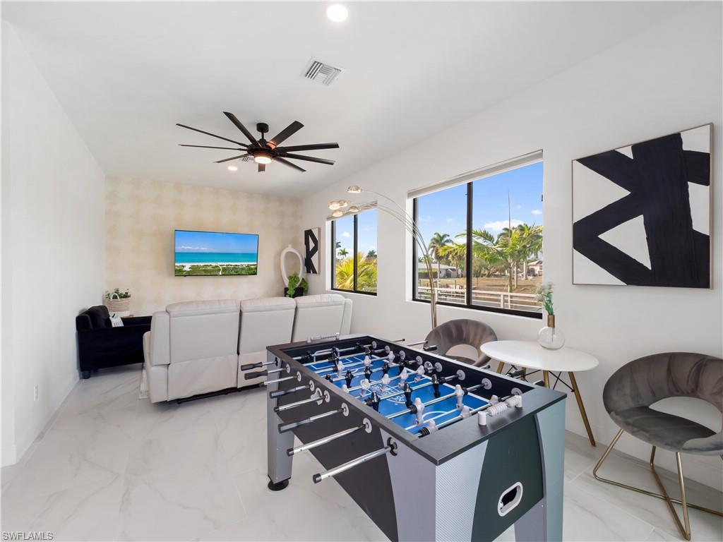Rec room with a ceiling fan, recessed lighting, and light marble finish flooring