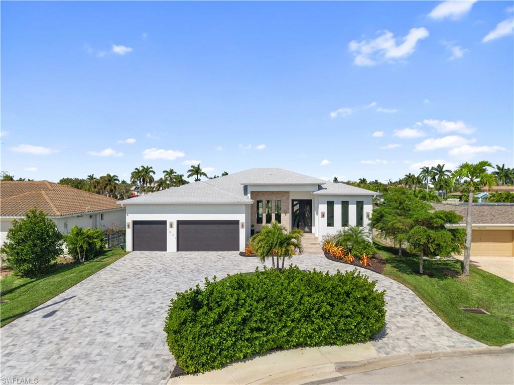 Prairie-style house with an attached garage, decorative driveway, stucco siding, and a front lawn
