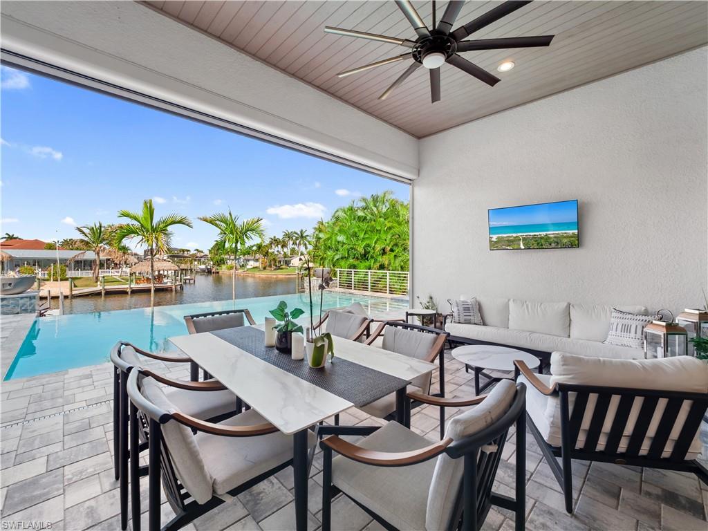 View of patio featuring ceiling fan, an infinity pool, and outdoor lounge area