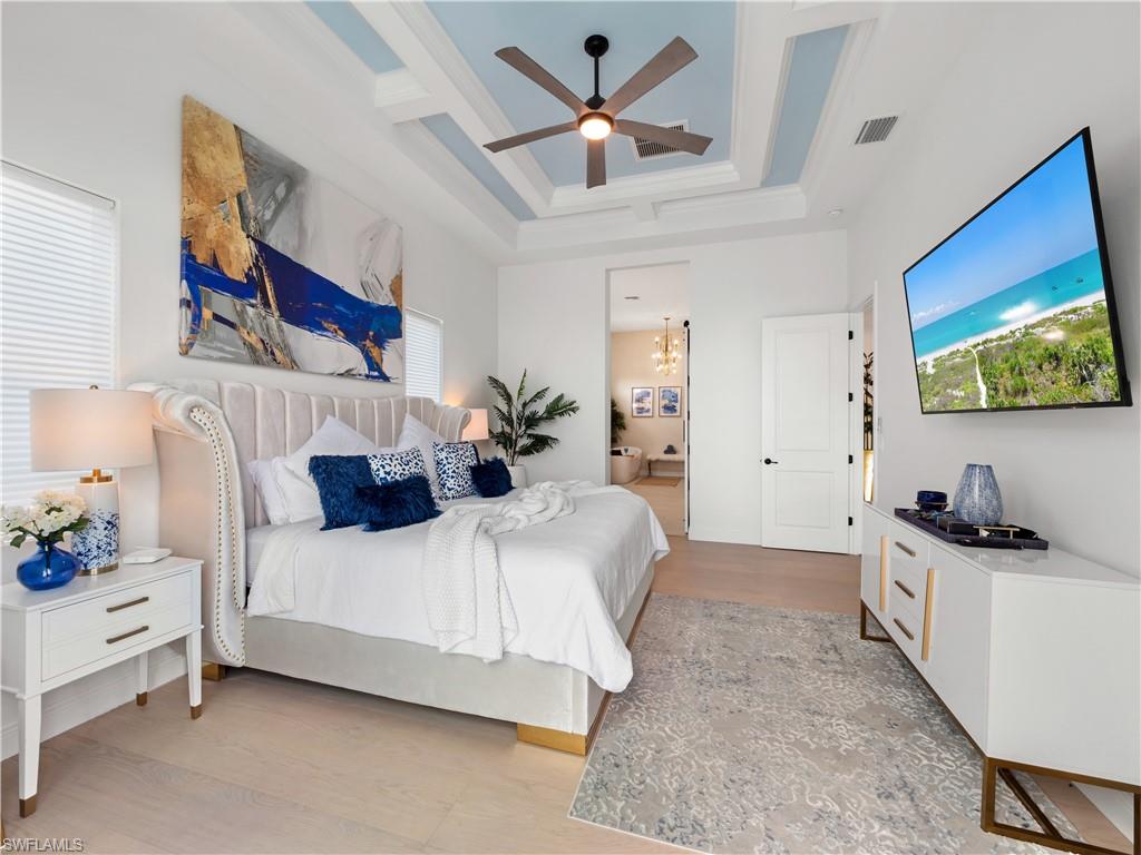 Bedroom with light wood-style floors, a ceiling fan, coffered ceiling, and hanging lights