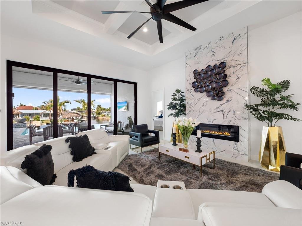 Living room with a ceiling fan, recessed lighting, a high end fireplace, and coffered ceiling