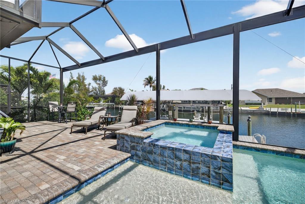 Relaxing pool / spa featuring glass enclosure, boat lift, and a water view