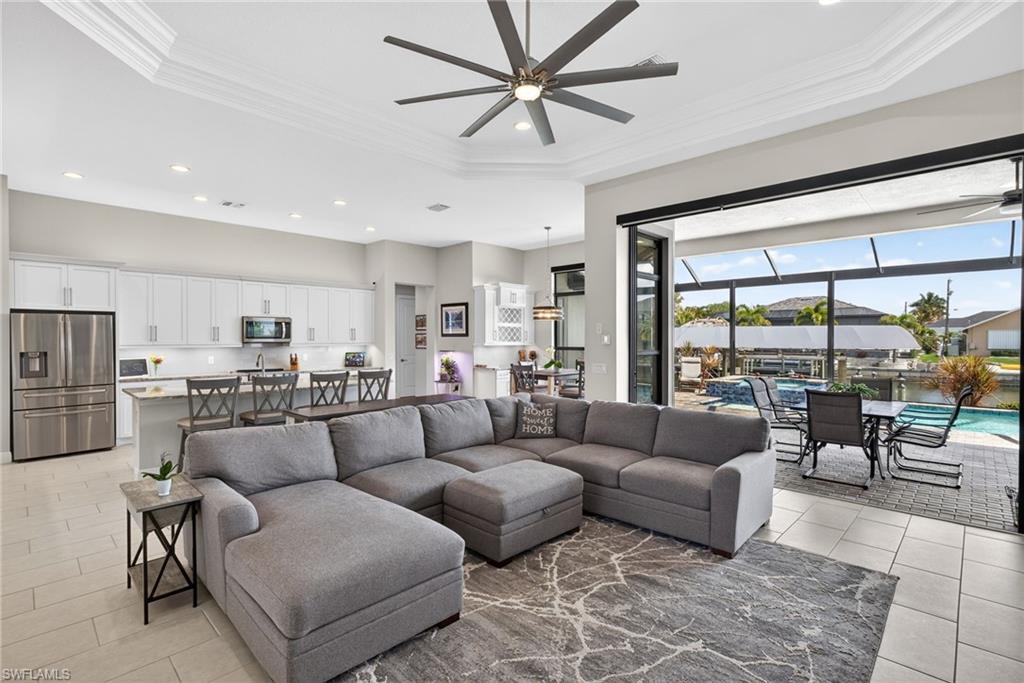 Living area with crown molding, a raised ceiling, and recessed lighting