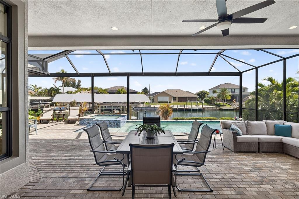 View of lanai with a pool with connected hot tub, dining and lounging areas, large dock, tiki bar and a beautiful water view