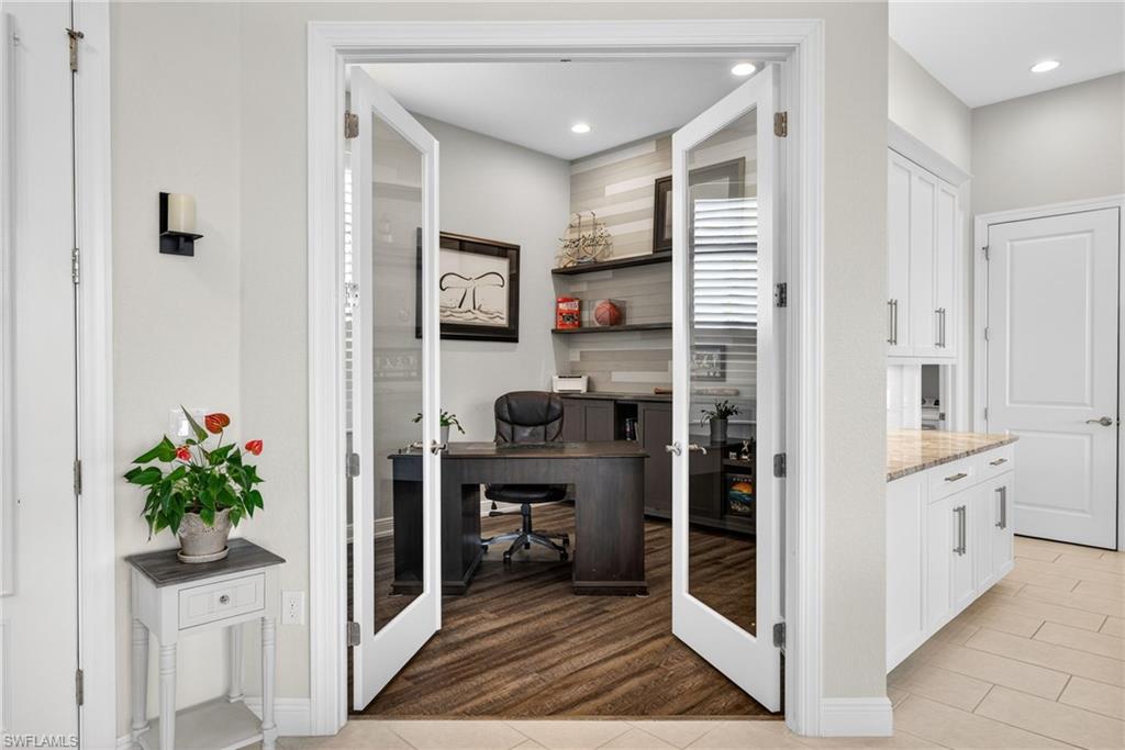 Office area with a custom wall with built in cabinets, french doors, light wood-style flooring, and recessed lighting