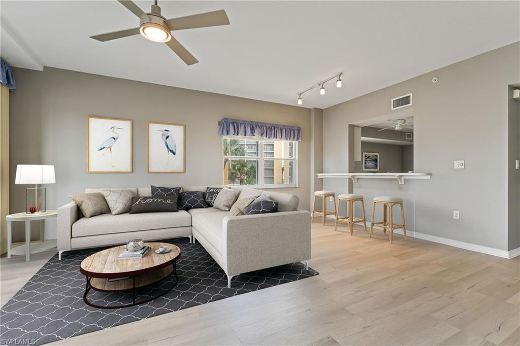 Living area with ceiling fan, light wood-style flooring, and track lighting