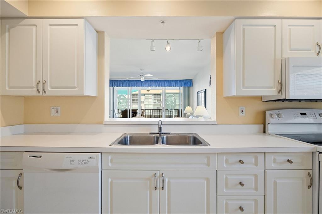 Kitchen featuring white appliances, light countertops, and white cabinetry