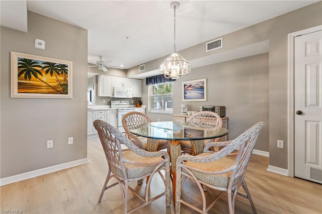 Dining area with ceiling fan, light wood-style floors, and a chandelier