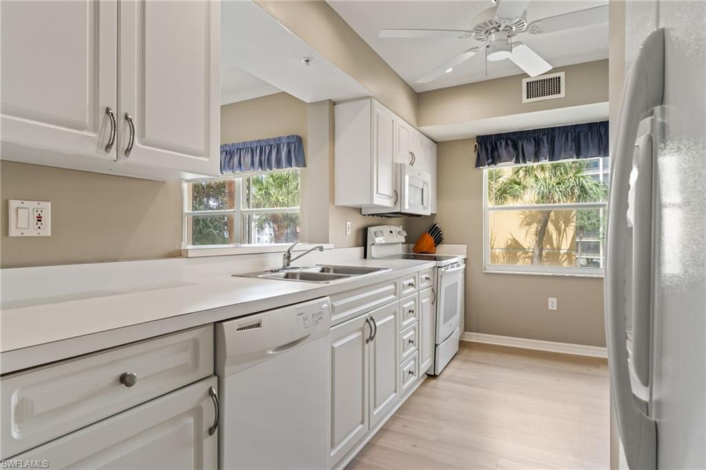 Kitchen featuring white appliances, white cabinetry, light countertops, ceiling fan, and light wood-type flooring