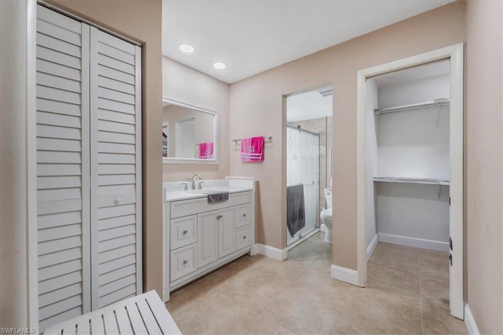 Full bath featuring vanity, a shower stall, a walk in closet, recessed lighting, and light tile patterned floors
