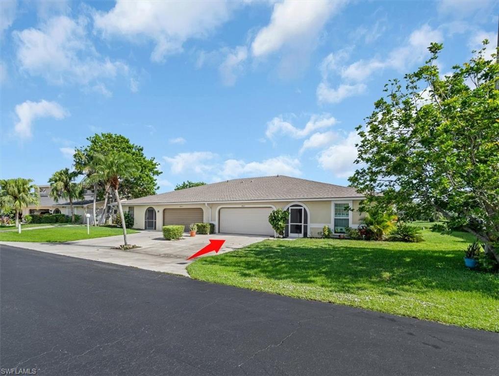 View of front of home with a front lawn, driveway, an attached garage, and stucco siding