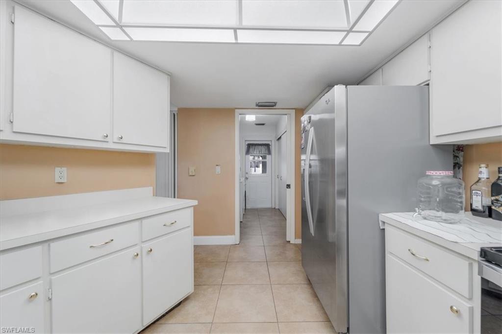 Kitchen featuring white cabinets, light countertops, and freestanding refrigerator