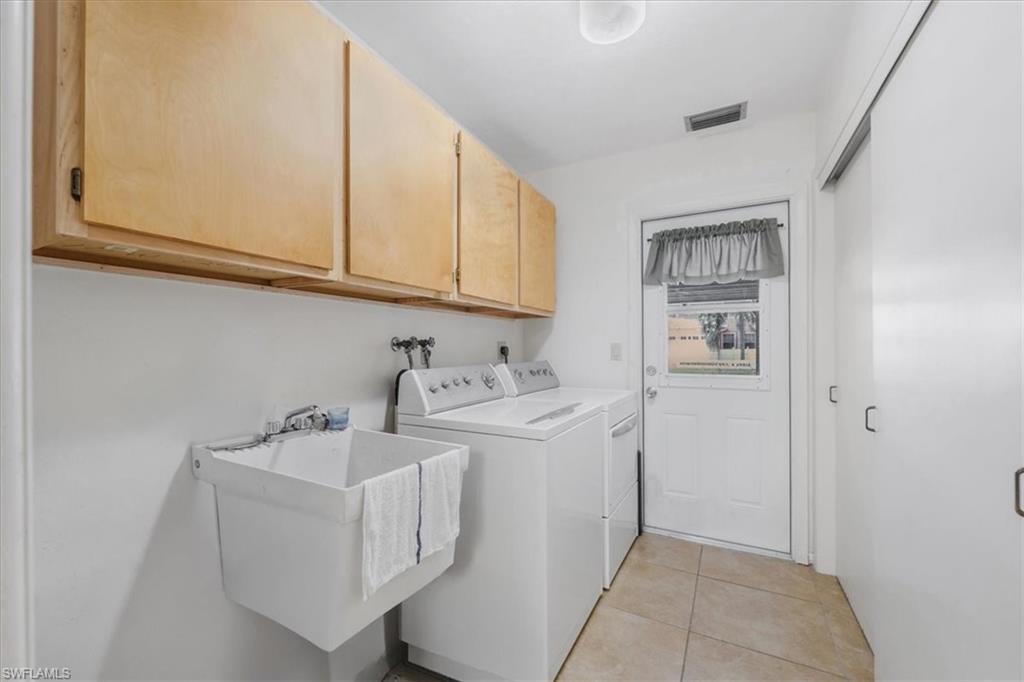 Laundry area with cabinet space, washer and clothes dryer, and light tile patterned floors