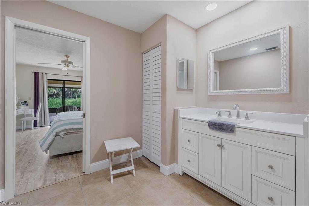 Ensuite bathroom featuring a closet, vanity, a ceiling fan, and light tile patterned floors