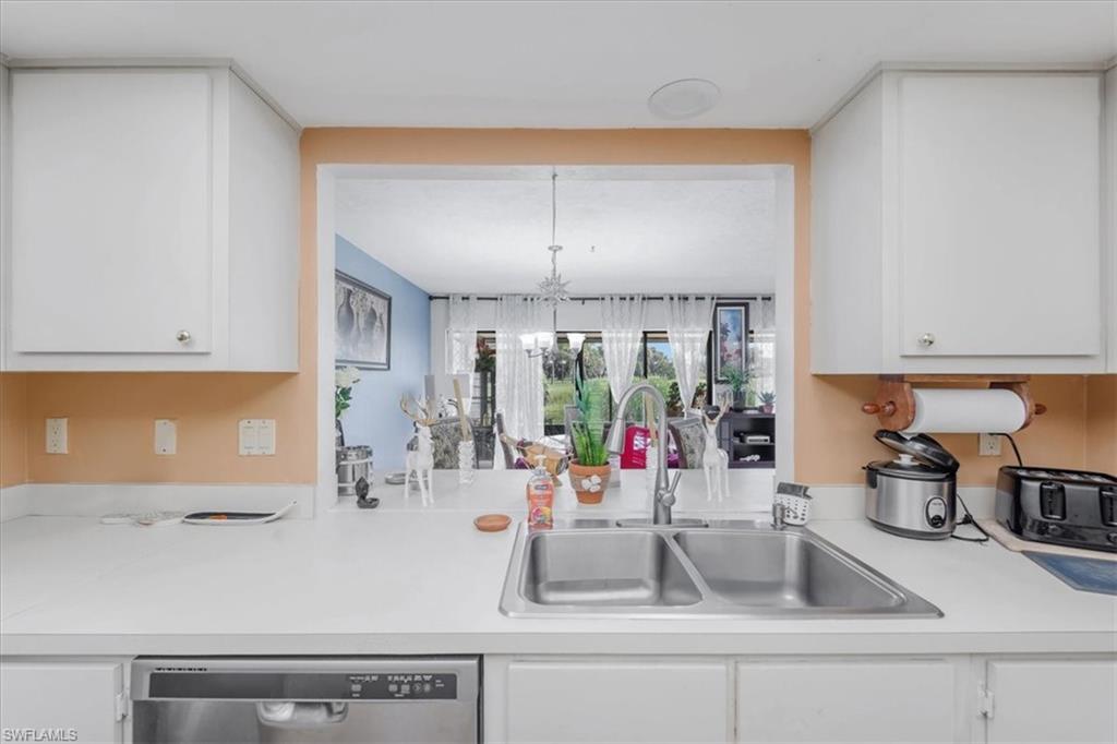 Kitchen with white cabinets, light countertops, and stainless steel dishwasher