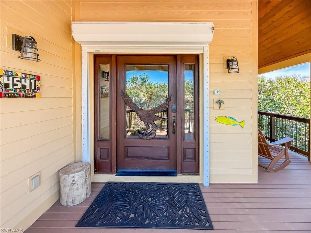 Entryway with high vaulted ceiling, a healthy amount of sunlight, wood finished floors, and a notable chandelier