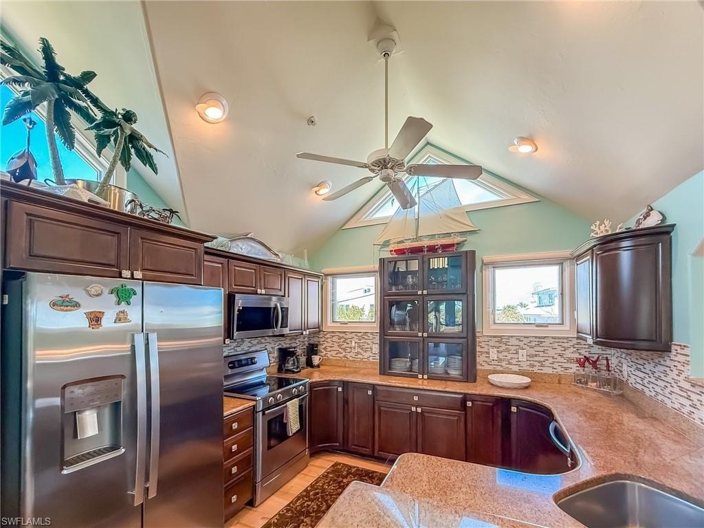 Kitchen featuring ceiling fan, a sink, visible vents, vaulted ceiling, and tasteful backsplash