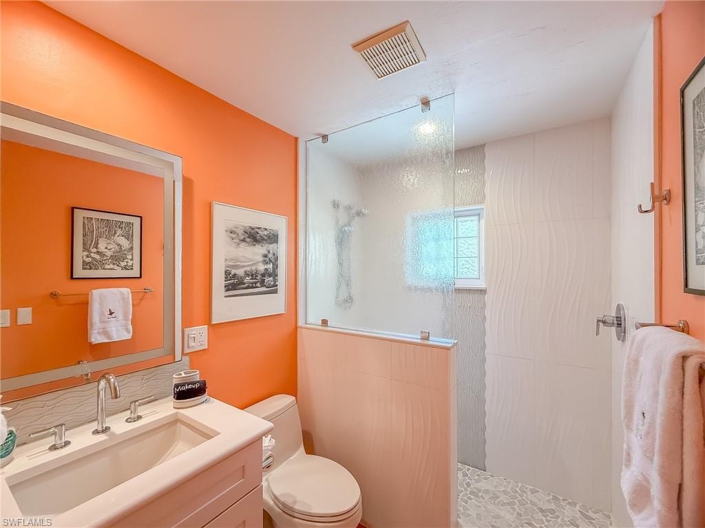 Full bathroom featuring visible vents, vanity, toilet, and walk in shower