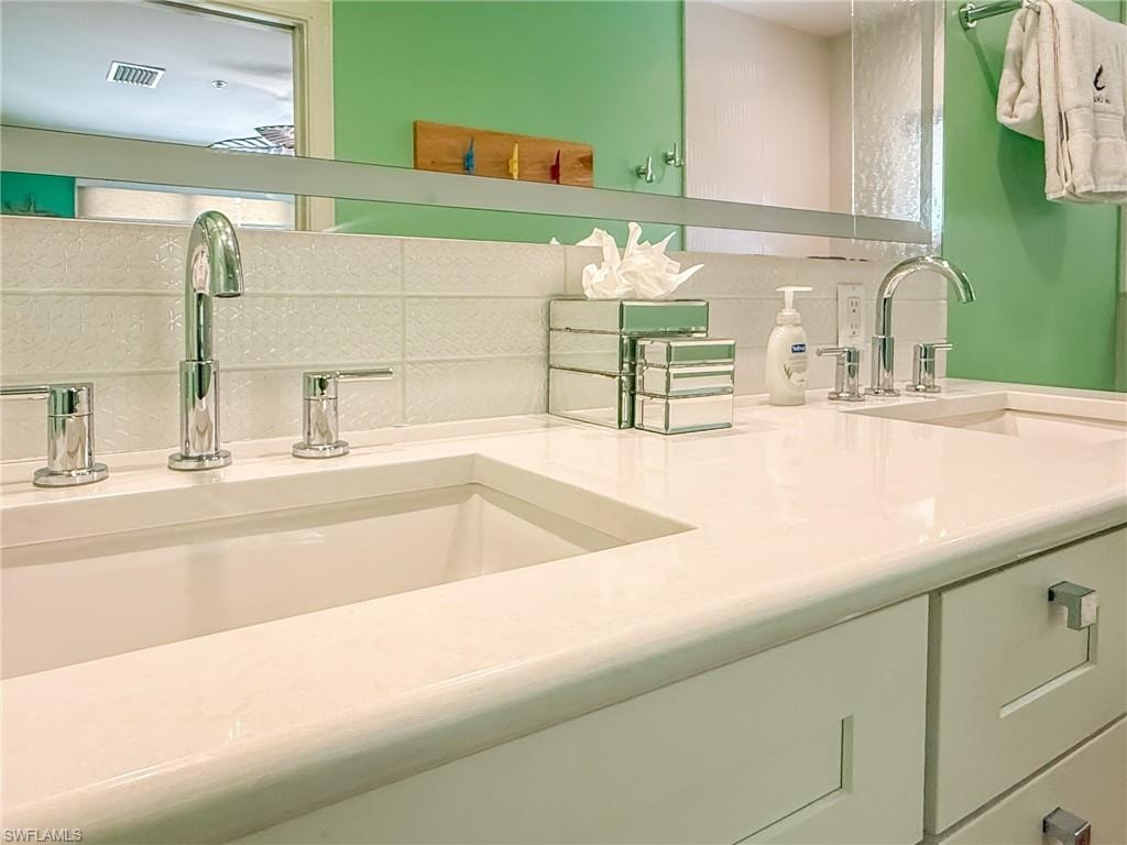 Kitchen featuring ceiling fan, a sink, visible vents, vaulted ceiling, and tasteful backsplash