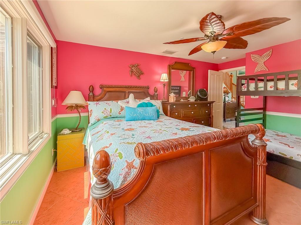 Bedroom featuring a ceiling fan, light tile patterned flooring, visible vents, and baseboards