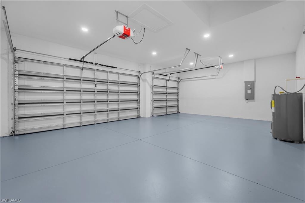 Garage with water heater, a garage door opener, electric panel, and recessed lighting