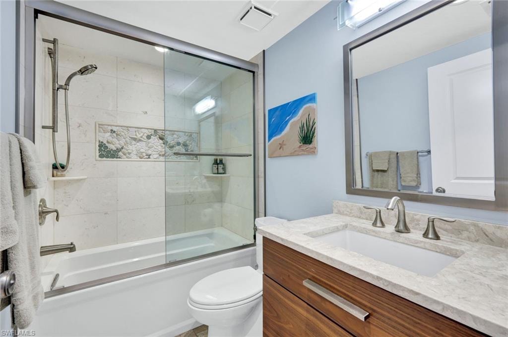 Bathroom with vanity and bath / shower combo with glass door