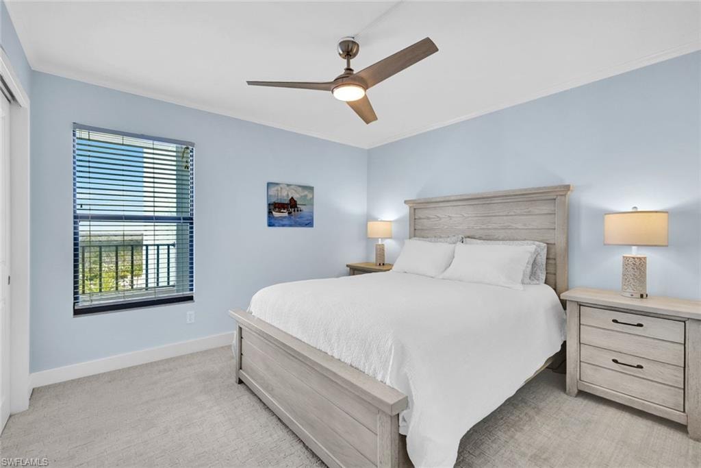 Bedroom with light carpet, ornamental molding, ceiling fan, and a closet