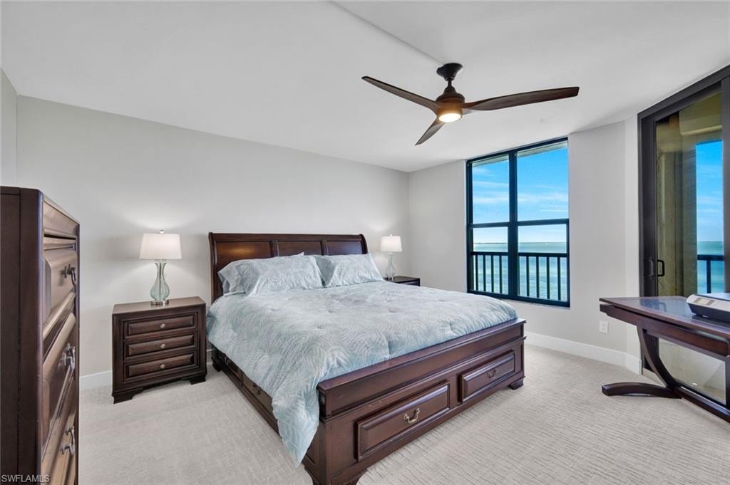 Bedroom with light colored carpet, ceiling fan, and a water view