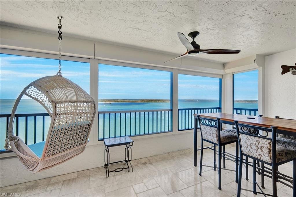 Sunroom / solarium with a water view and a textured ceiling