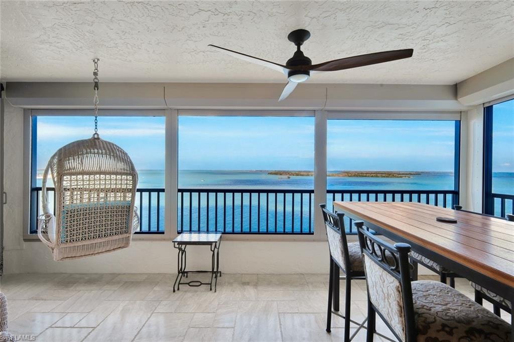 Sunroom / solarium with a water view and a textured ceiling