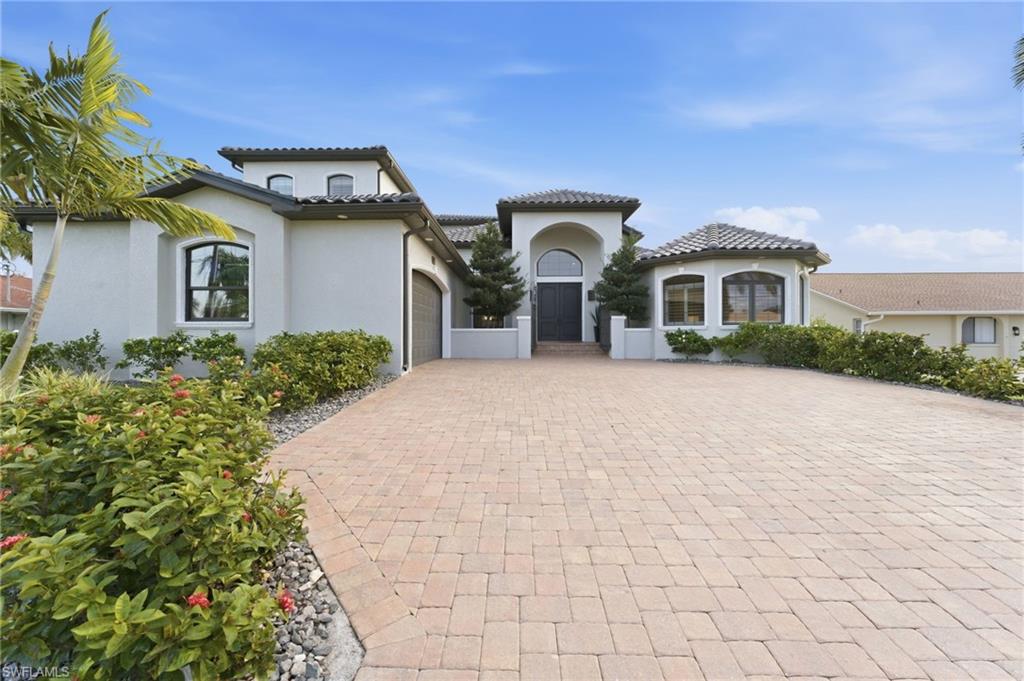 Mediterranean / spanish-style home featuring an attached garage, stucco siding, driveway, and a tile roof
