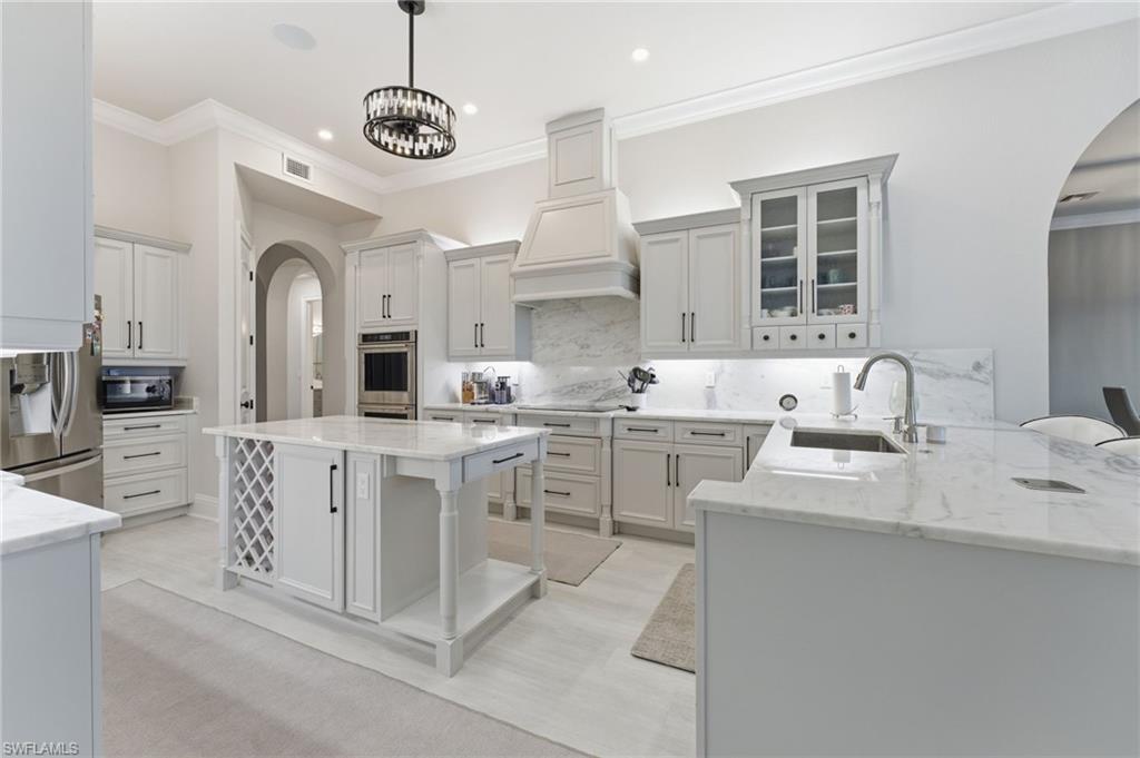 Kitchen with arched walkways, a breakfast bar area, light stone counters, and ornamental molding