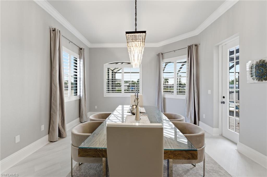 Dining area with a chandelier, ornamental molding, and light wood-type flooring