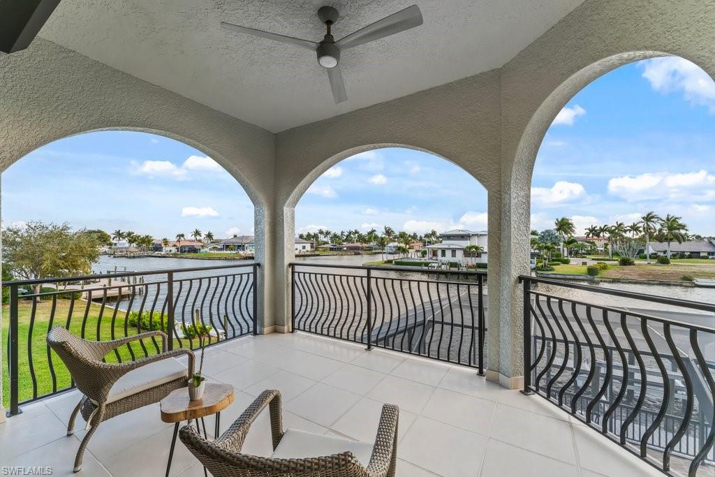 Balcony with a residential view, ceiling fan, and a water view