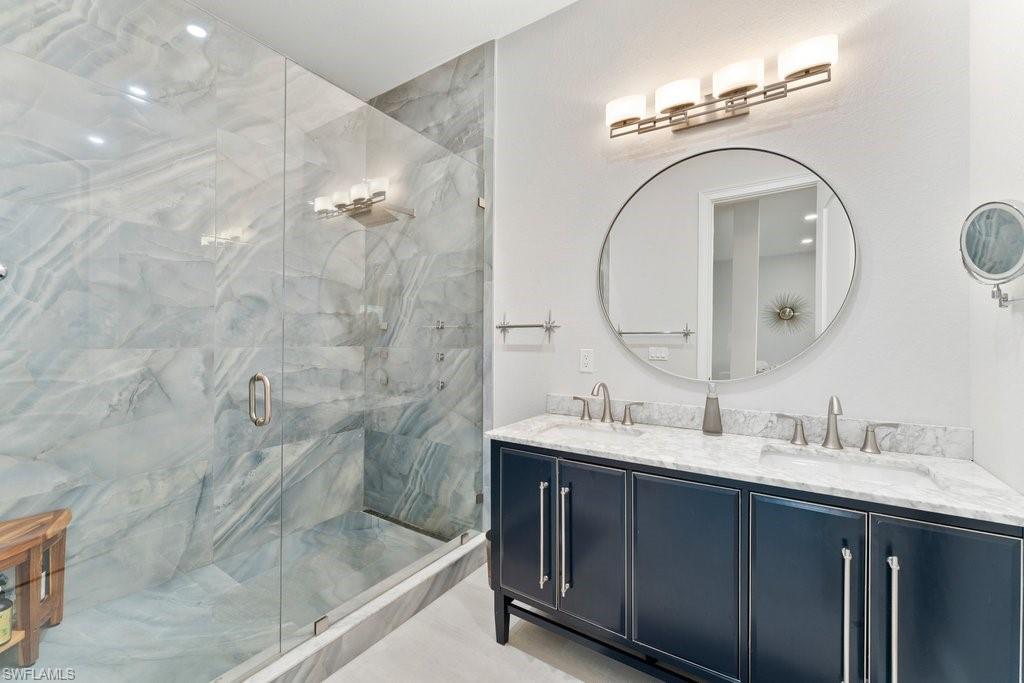 Full bathroom featuring double vanity and a marble finish shower