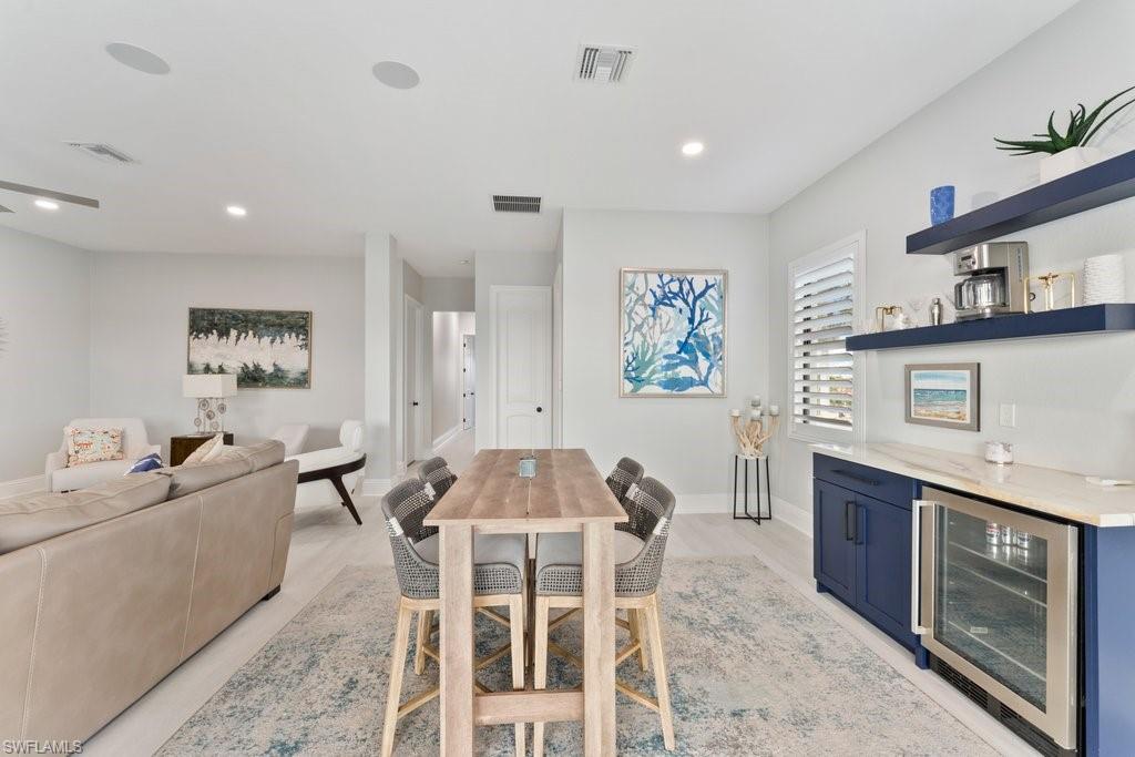 Dining area with beverage cooler, light wood finished floors, and recessed lighting