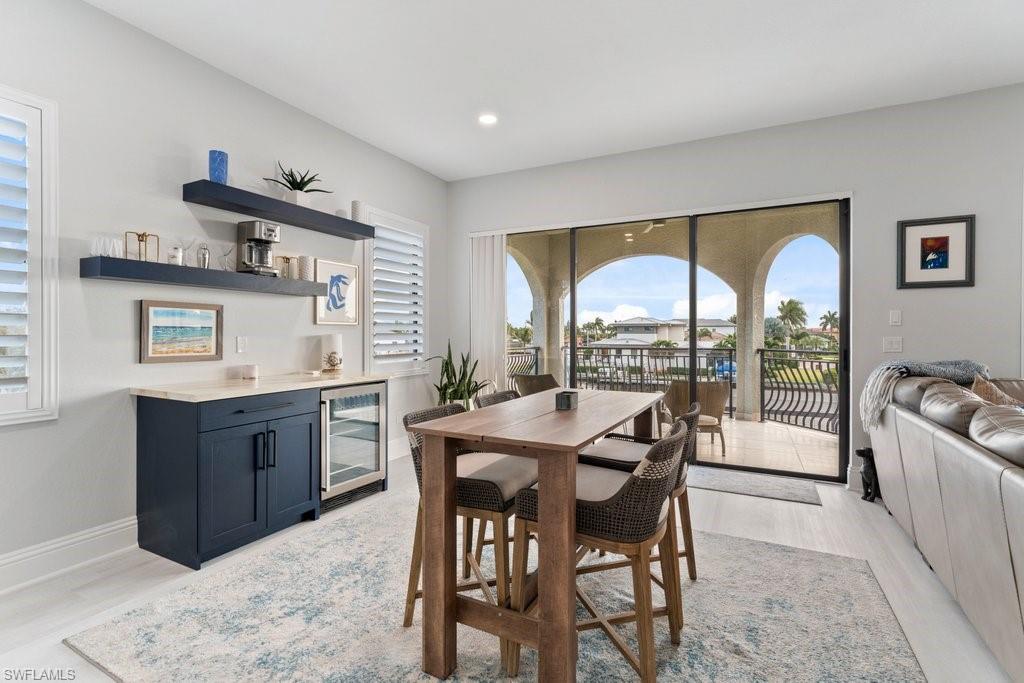 Dining area with beverage cooler, light wood-type flooring, and a bar