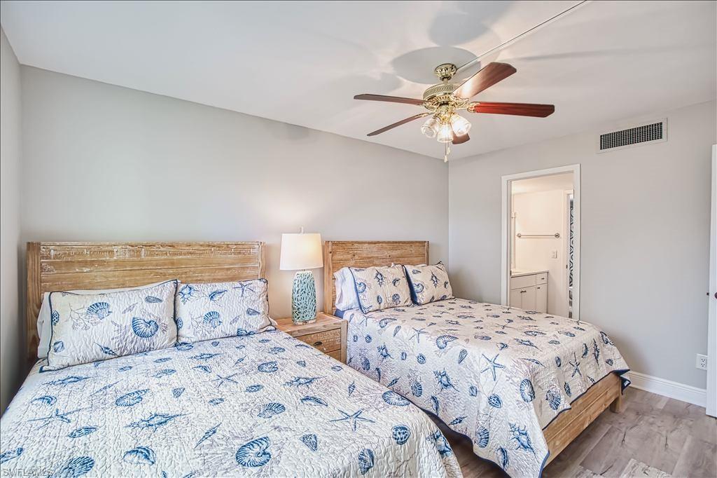 Bedroom with ensuite bath, a ceiling fan, and wood finished floors