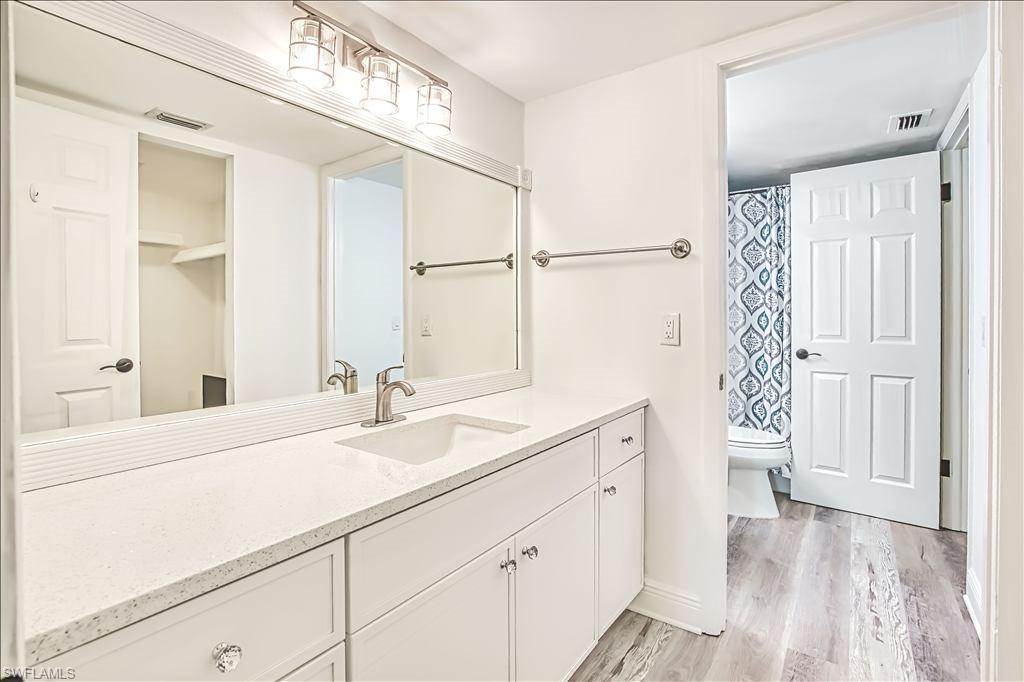 Full bath with vanity, a shower with shower curtain, and light wood finished floors