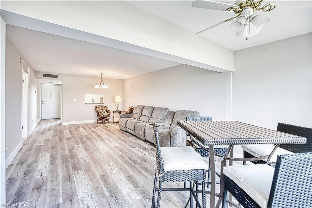 Living area featuring light wood-type flooring, hanging lights, and ceiling fan
