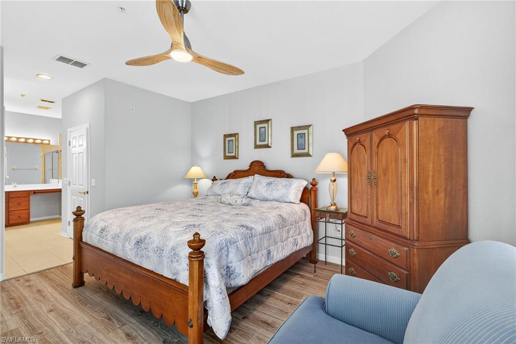 Bedroom with light wood-style floors, a ceiling fan, and ensuite bath