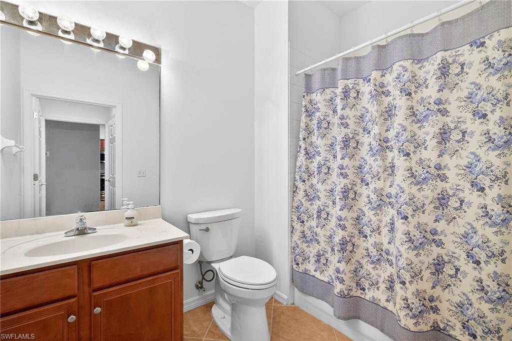 Full bath with vanity, light tile patterned floors, and shower / bathtub combination with curtain