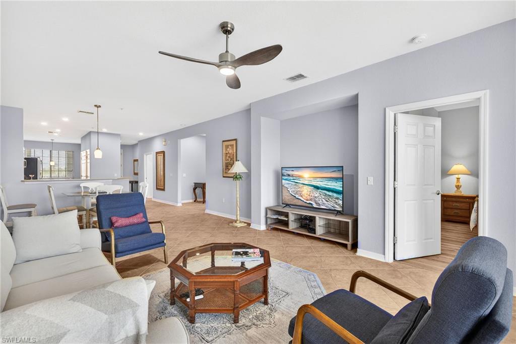 Living room with ceiling fan, light tile patterned floors, and recessed lighting