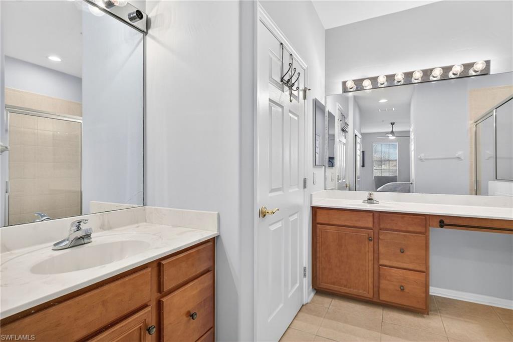 Bathroom featuring two vanities, ensuite bathroom, a stall shower, and light tile patterned flooring