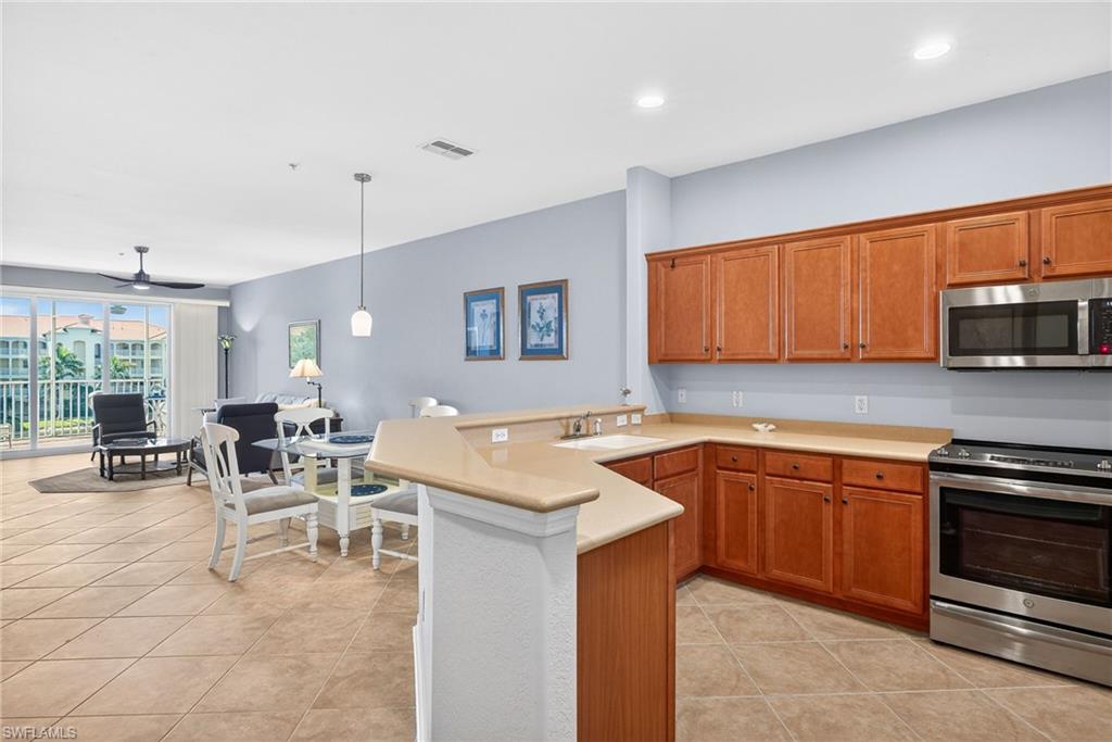 Kitchen featuring stainless steel appliances, wood finish cabinets, light countertops, a peninsula, and open floor plan