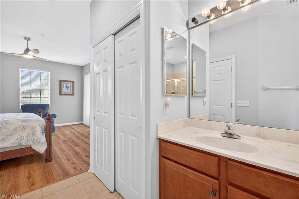 Ensuite bathroom with vanity, light tile patterned flooring, a closet, and a ceiling fan