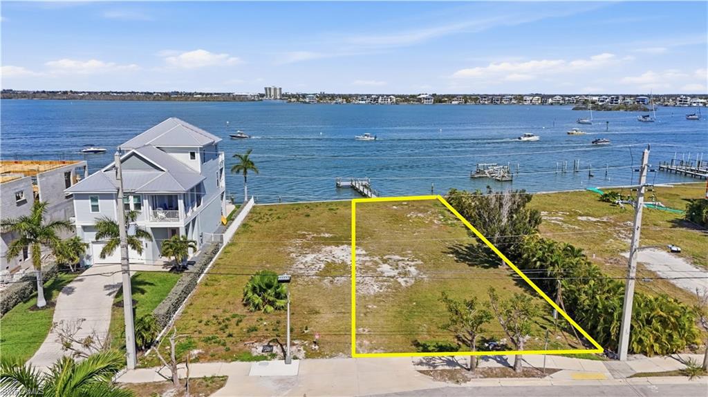 Aerial overview of property's location with property parcel outlined and a nearby body of water - Virtually Edited Image
