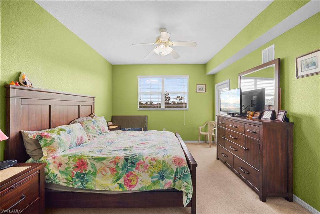 Bedroom featuring light carpet, a textured wall, and a ceiling fan
