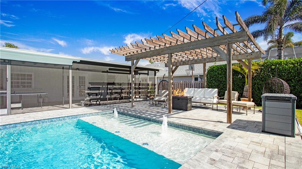 View of swimming pool featuring a pergola, patio surround, an outdoor living space with a fire pit, and french doors
